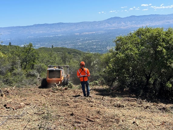 A man operates remote-controlled machinery to conduct ecologically sensitive vegetation removal
