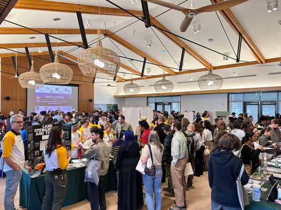 A large room packed full of informational booths and career fair visitors 