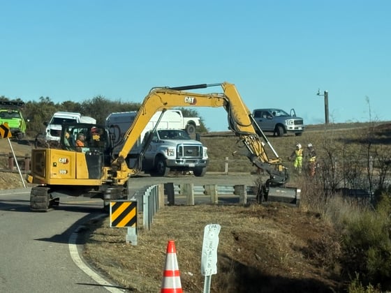 Crew work with an excavator to remove vegetation along Page Mill Road