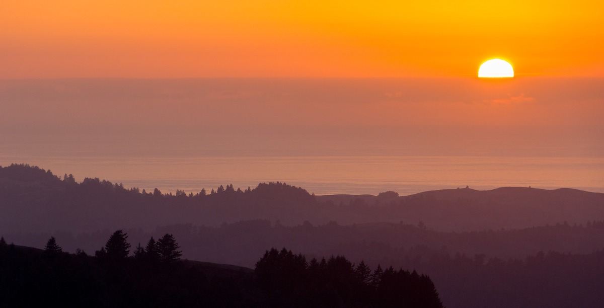 Vista of a sunset over the water from Russian Ridge