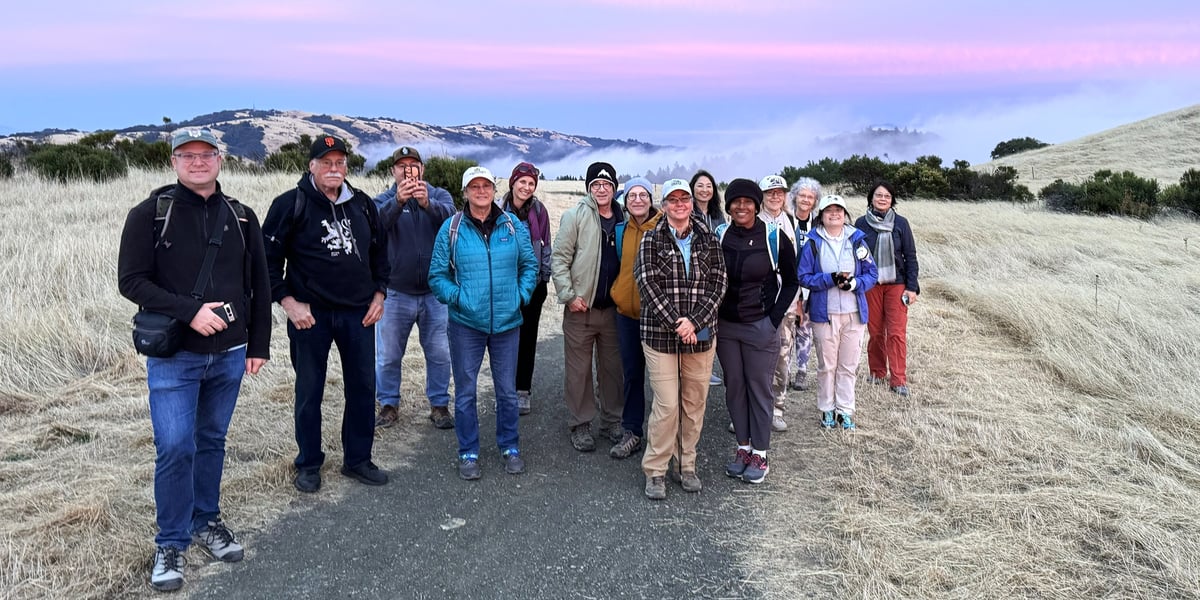 A group of people on a docent-led hike in a Midpen preserve at sunset.