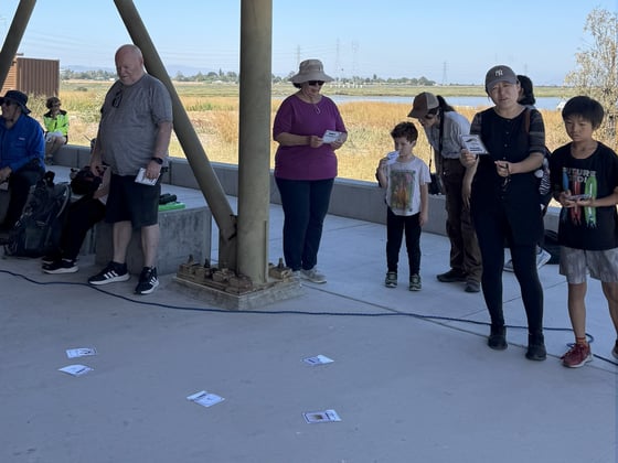 A crowd of people admire illustrations of birds that may be spotted at Ravenswood Open Space Preserve