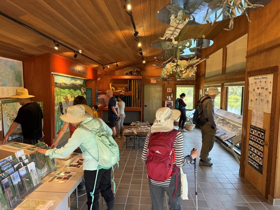 A group of visitors interact with various exhibits and educational materials in the Daniels Nature Center