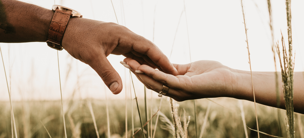 Photo of two hands over grassland