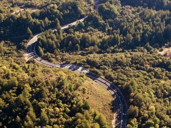 A highway winds through heavily forested hills